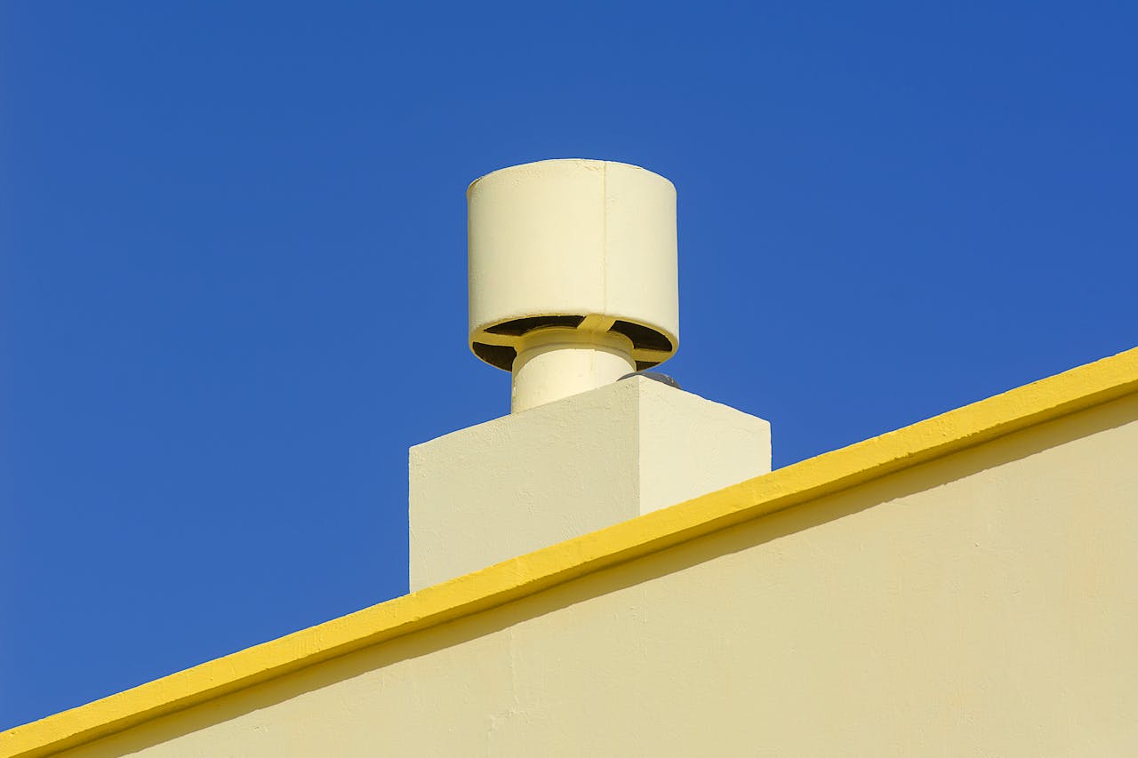 hero-img-02 Yellow industrial chimney against a vibrant blue sky, representing modern architecture.